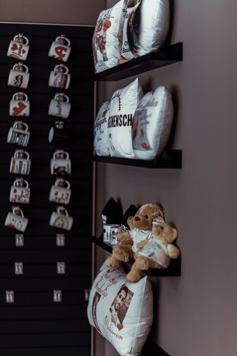 Regale mit bedruckten Kissen, Tassen und Teddys